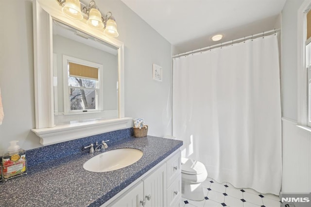 bathroom featuring toilet, vanity, and a shower with curtain