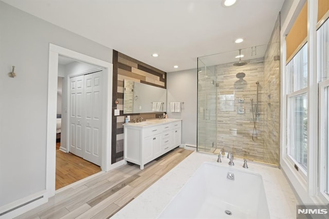 bathroom with a tub to relax in, wood finished floors, recessed lighting, a shower stall, and vanity