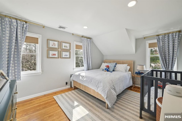 bedroom featuring baseboards, multiple windows, light wood-style floors, and lofted ceiling