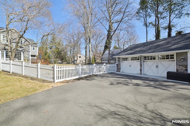 detached garage featuring fence and a residential view