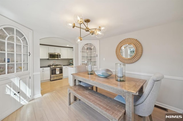 dining area with an inviting chandelier, light wood-style flooring, visible vents, and baseboards