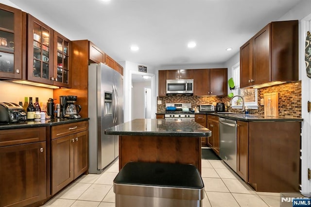 kitchen featuring a sink, a kitchen island, appliances with stainless steel finishes, and light tile patterned floors