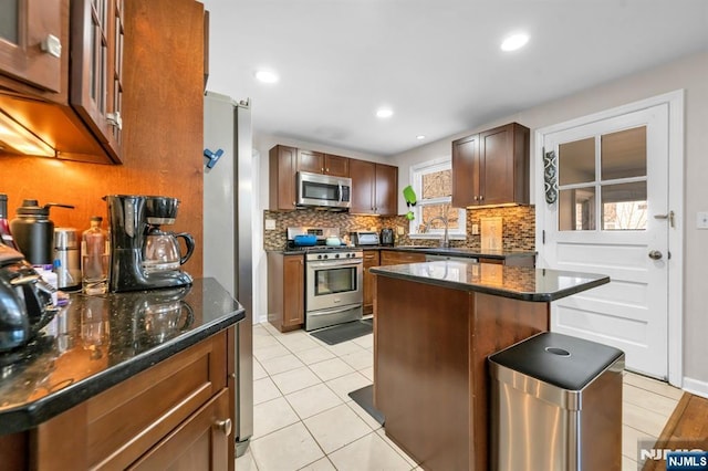 kitchen featuring dark stone countertops, light tile patterned flooring, tasteful backsplash, and appliances with stainless steel finishes