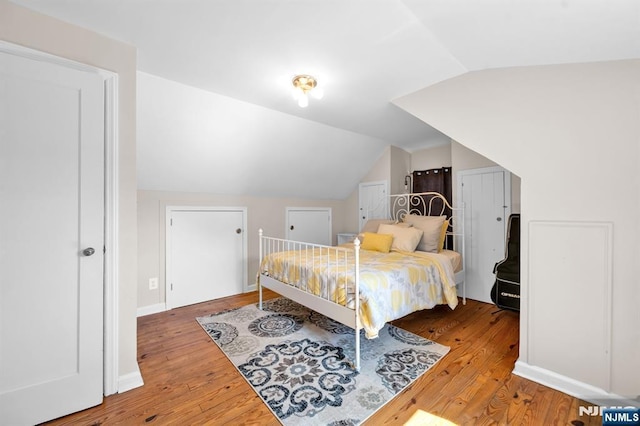 bedroom with baseboards, lofted ceiling, and wood finished floors