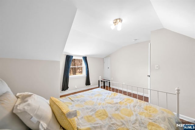 bedroom with baseboards, lofted ceiling, and wood finished floors