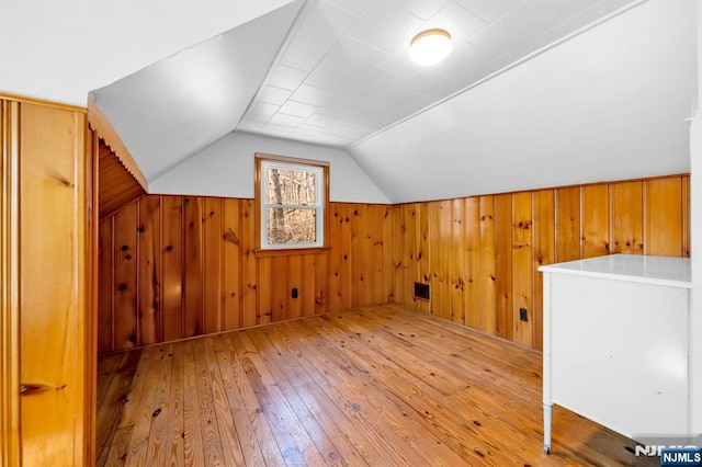 bonus room with vaulted ceiling, wood walls, and wood-type flooring