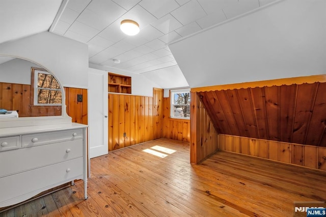 bonus room featuring lofted ceiling, light wood-style flooring, and wood walls