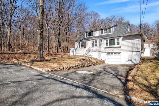 view of front of home featuring an attached garage, a shingled roof, and driveway