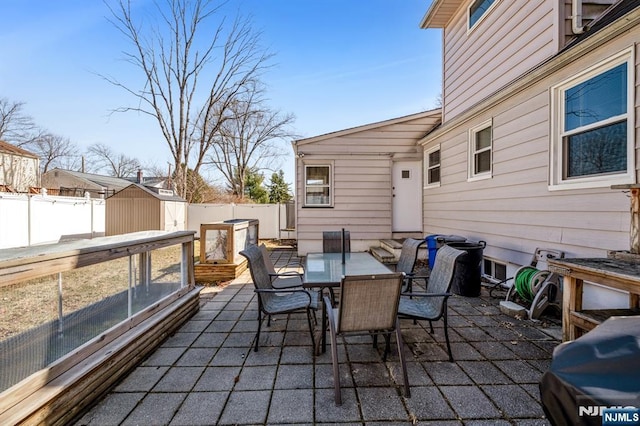 view of patio / terrace with a storage unit, a fenced backyard, an outbuilding, and outdoor dining space