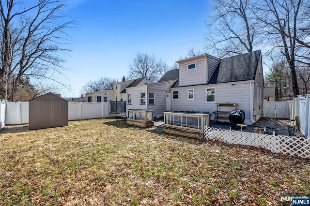 rear view of house featuring an outdoor structure, a yard, a fenced backyard, and a shed