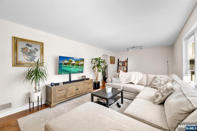 living area featuring visible vents, rail lighting, wood finished floors, and baseboards