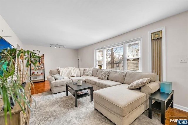 living area featuring track lighting, light wood-type flooring, and baseboards