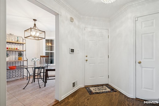 entrance foyer featuring visible vents, baseboards, an inviting chandelier, and ornamental molding