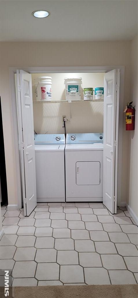 laundry room with laundry area, light floors, baseboards, and washer and clothes dryer