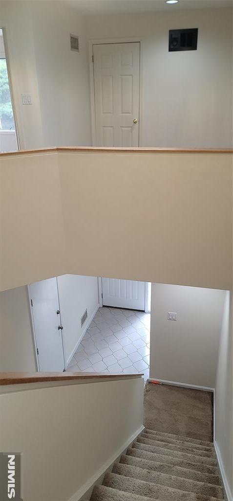 stairway featuring visible vents and baseboards