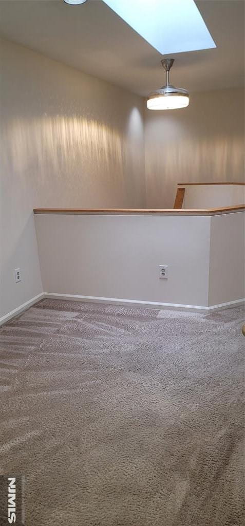 carpeted spare room with a skylight and baseboards