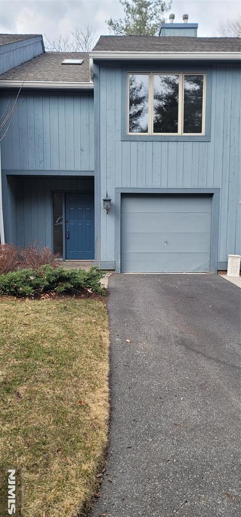 view of front of property with aphalt driveway, an attached garage, and a shingled roof