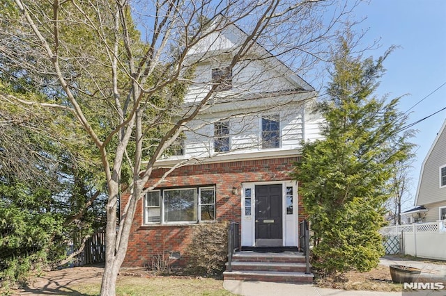 american foursquare style home featuring crawl space, brick siding, and fence