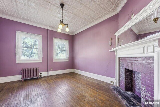 unfurnished living room with radiator, an ornate ceiling, baseboards, and crown molding