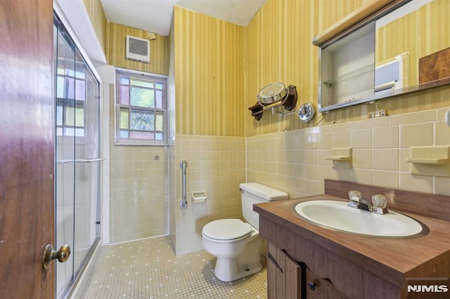 bathroom with visible vents, toilet, tile walls, and wallpapered walls