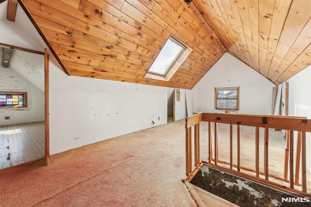 additional living space featuring wooden ceiling, vaulted ceiling with skylight, and carpet