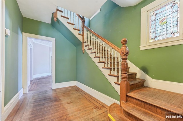 staircase featuring baseboards and wood finished floors