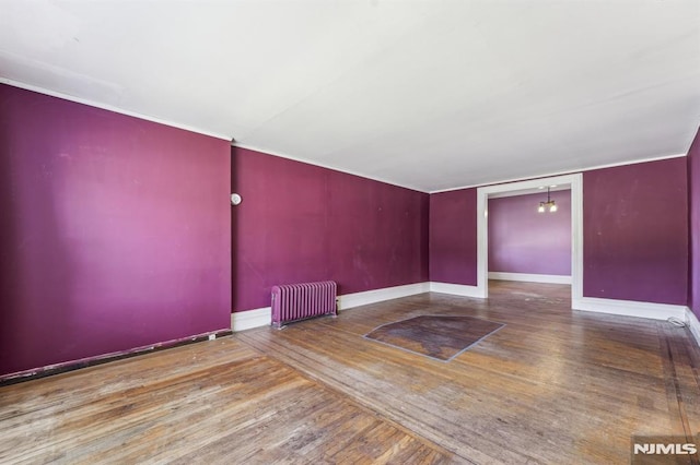 unfurnished room with an inviting chandelier, hardwood / wood-style flooring, radiator heating unit, and baseboards