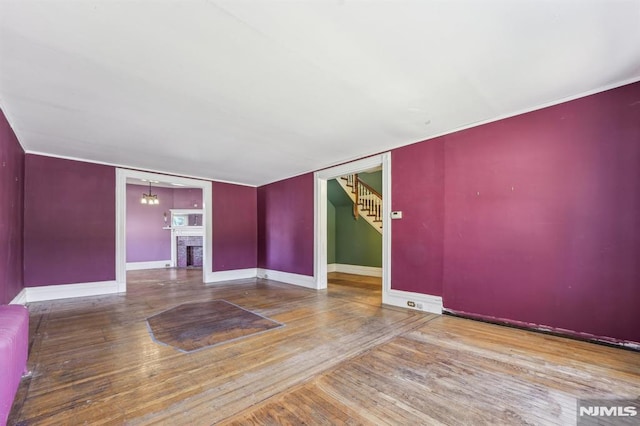 spare room with hardwood / wood-style floors, stairway, a fireplace, and baseboards