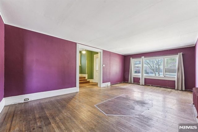 unfurnished living room featuring hardwood / wood-style floors, stairway, and baseboards