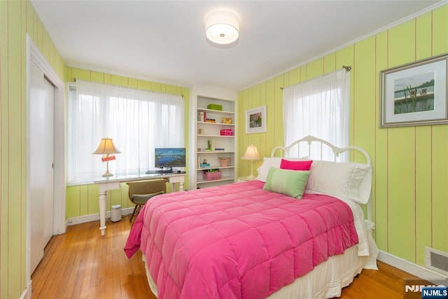 bedroom with hardwood / wood-style floors, visible vents, and ornamental molding