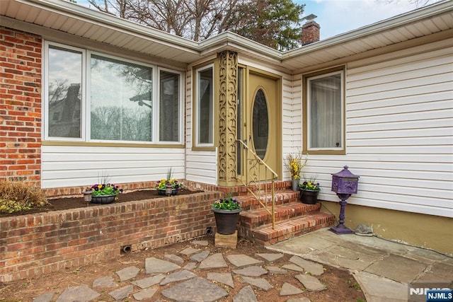 property entrance featuring brick siding and a chimney