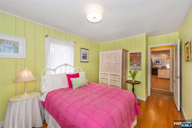 bedroom with wood finished floors and crown molding