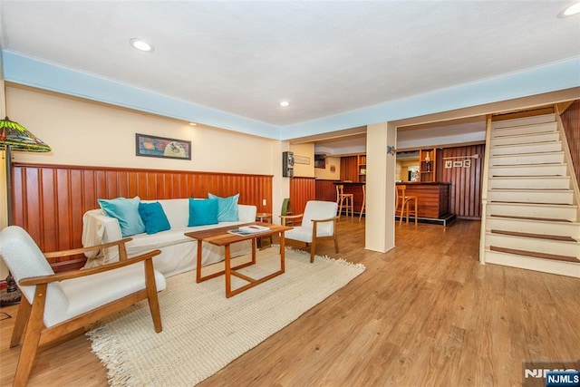 living area with recessed lighting, a bar, wood finished floors, and stairs