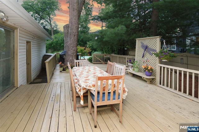 deck at dusk featuring outdoor dining space