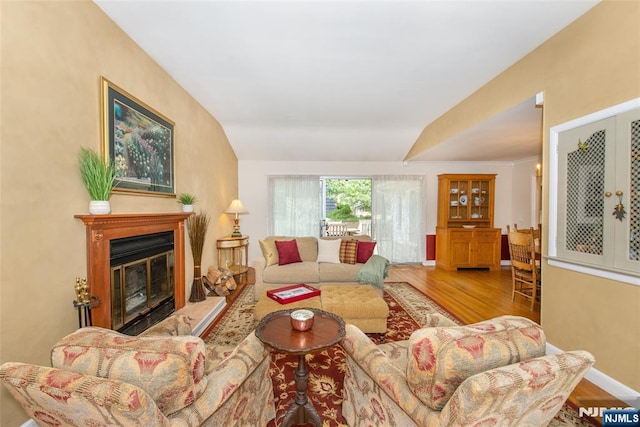 living area with a glass covered fireplace, baseboards, and wood finished floors