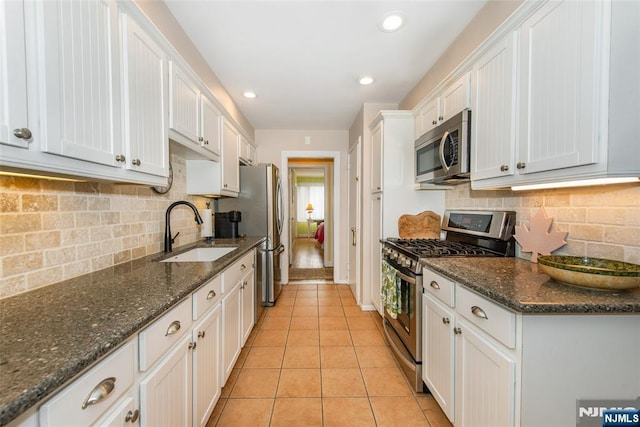 kitchen featuring light tile patterned flooring, white cabinets, appliances with stainless steel finishes, and a sink