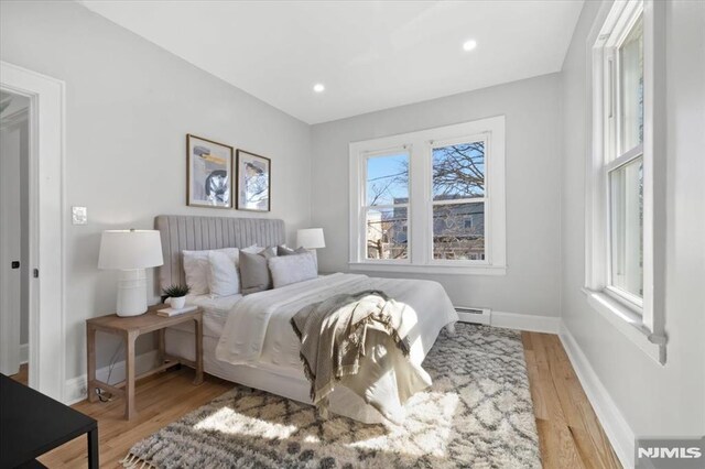 bedroom featuring recessed lighting, baseboards, baseboard heating, and light wood-style flooring