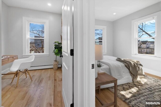 bedroom featuring light wood finished floors, recessed lighting, baseboards, and a baseboard radiator