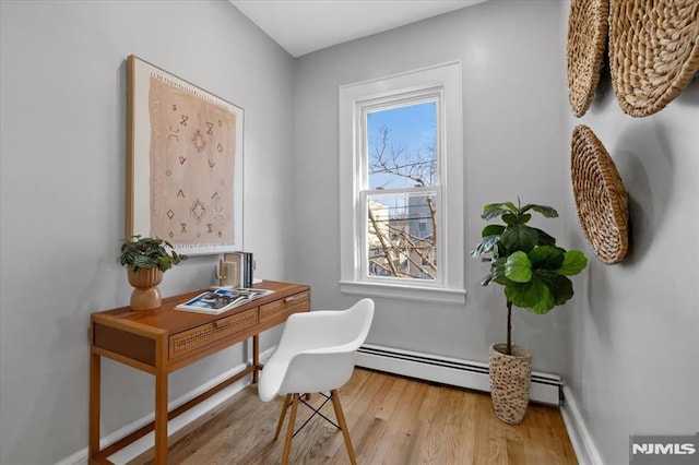 office with a baseboard radiator, baseboards, and light wood finished floors