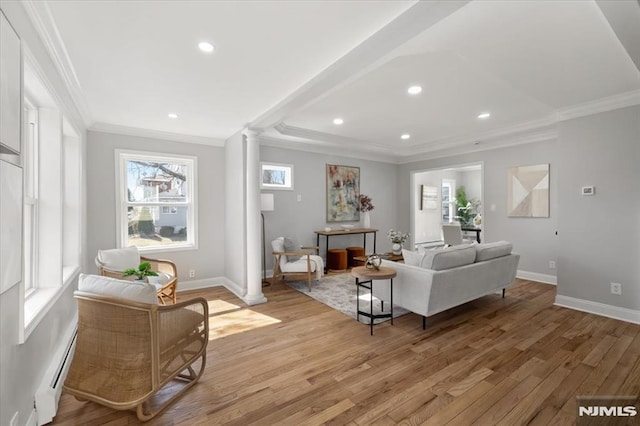 living area featuring light wood finished floors, baseboards, a baseboard heating unit, and ornate columns