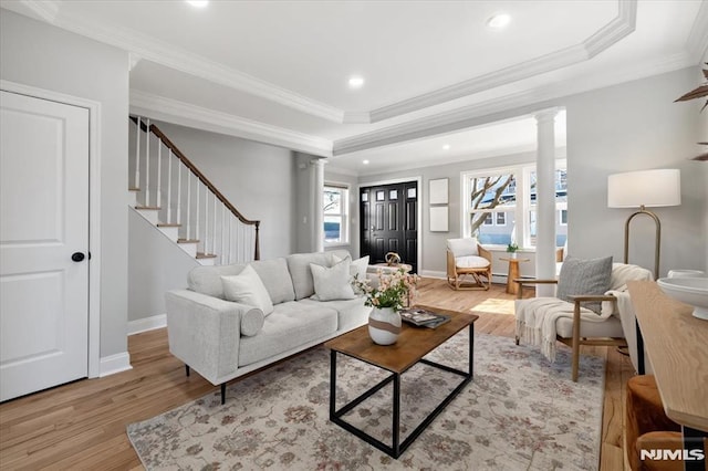 living room with stairway, light wood-style flooring, baseboards, and decorative columns