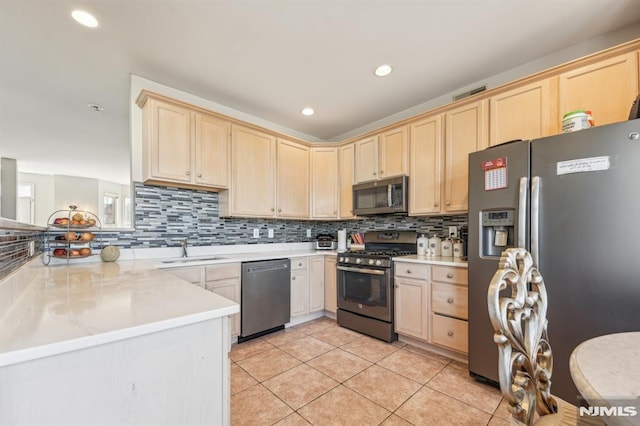 kitchen with light brown cabinets, light tile patterned flooring, a sink, stainless steel appliances, and tasteful backsplash