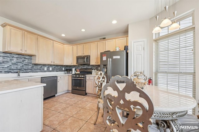 kitchen featuring light brown cabinetry, stainless steel appliances, and a sink