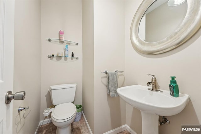 half bathroom featuring toilet, baseboards, and a sink