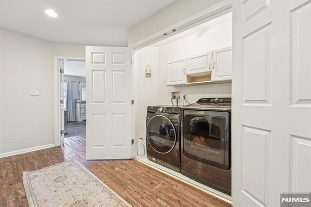 laundry room featuring washer and clothes dryer, cabinet space, light wood-type flooring, and baseboards