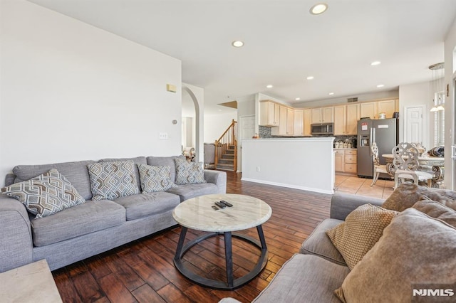 living room with stairs, recessed lighting, light wood-style floors, and arched walkways