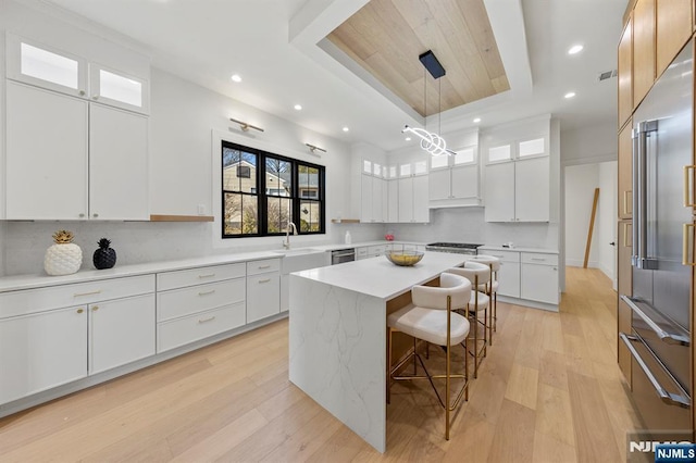 kitchen featuring a breakfast bar area, a kitchen island, stainless steel appliances, a raised ceiling, and tasteful backsplash