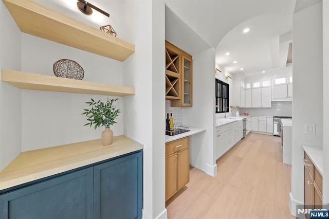 bar featuring recessed lighting, tasteful backsplash, stove, and light wood finished floors