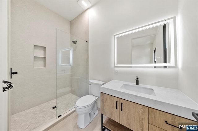 bathroom with vanity, toilet, and a tile shower