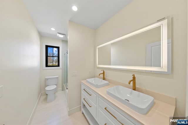 bathroom featuring toilet, baseboards, a shower with shower door, and a sink